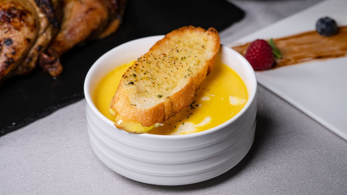 Bol de soupe dorée servie avec une tranche de pain grillé posée dessus