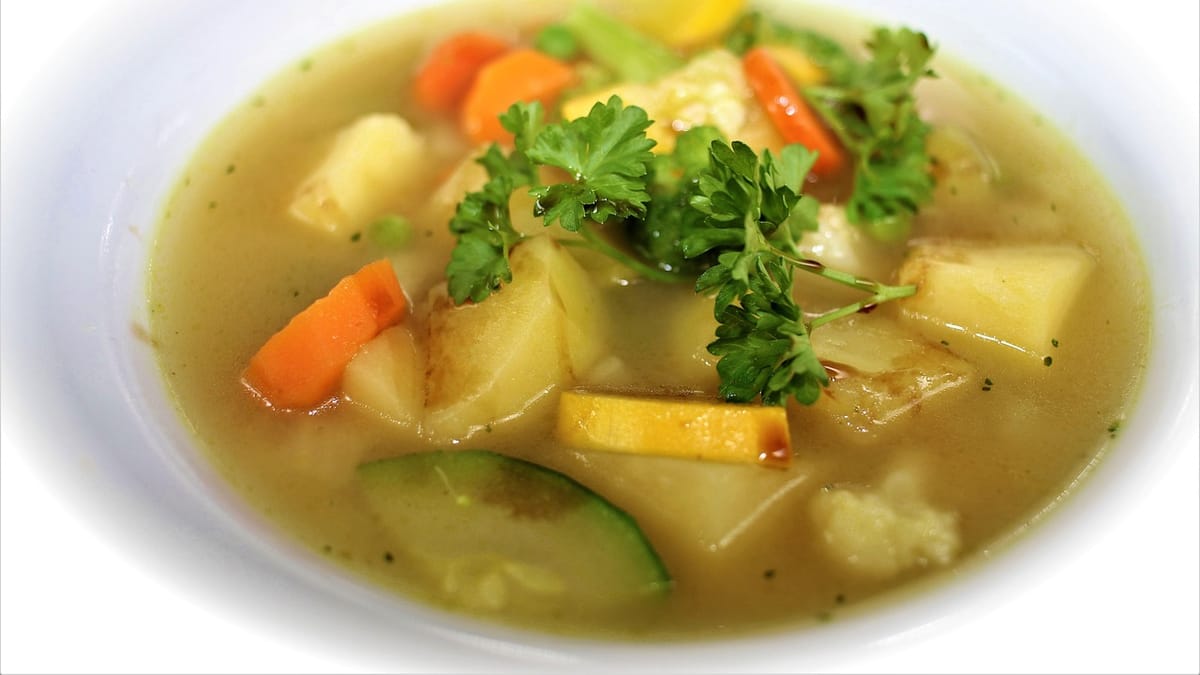 Assiette de soupe de légumes claire aux morceaux de pomme de terre, carotte et courgette, avec du persil