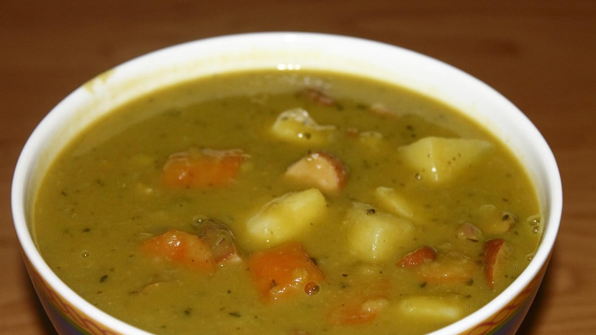 Bol de soupe de pois cassés épaisse avec pommes de terre, carottes et rondelles de saucisse